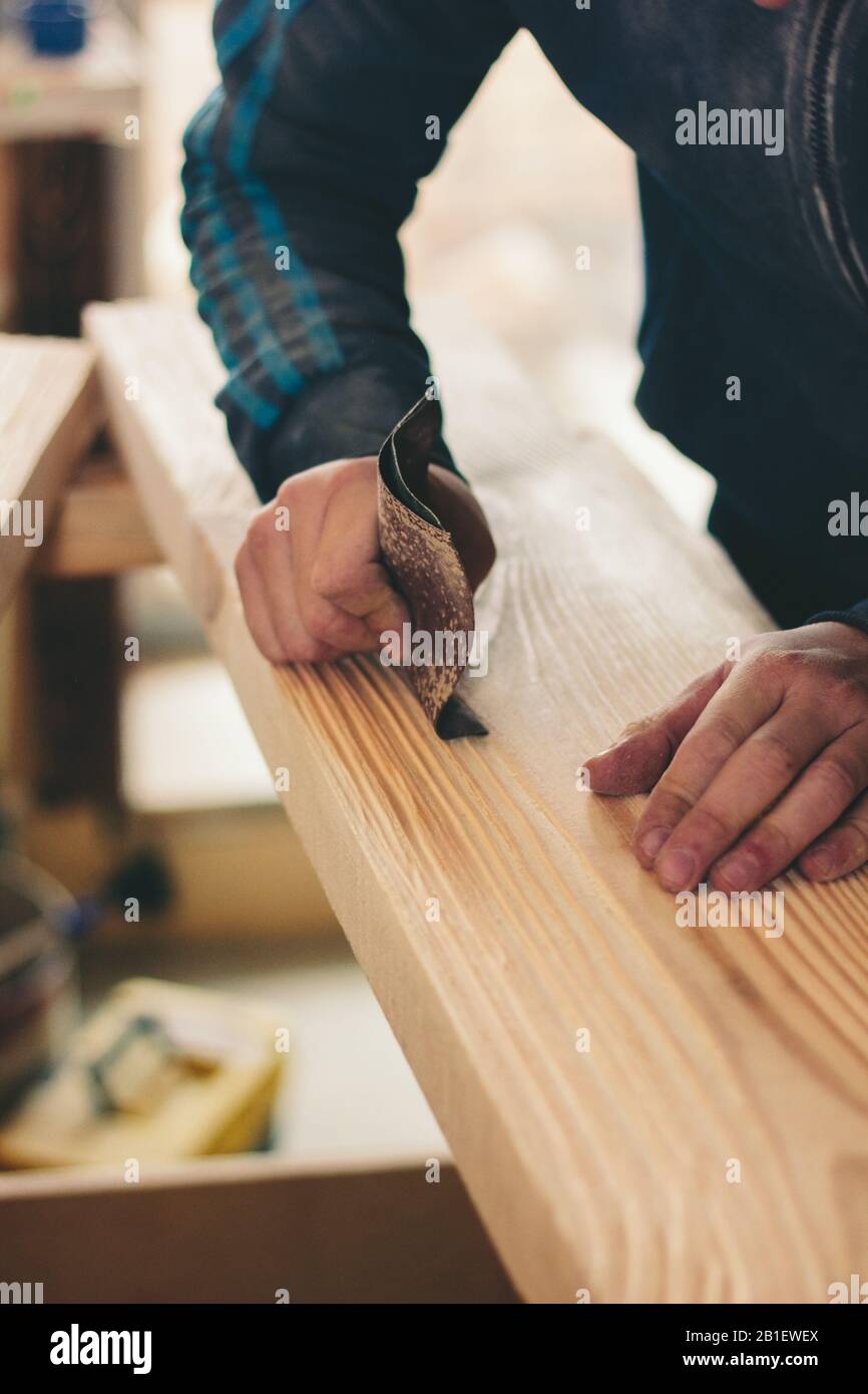 hands with the sandpaper treat the wooden plank. Great photo for your