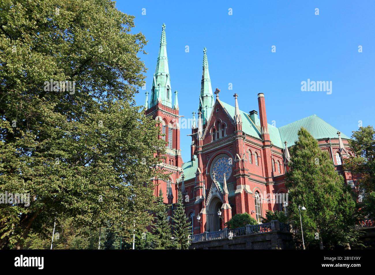 Famous gothic red church historic architecture landmark in Helsinki, Finland with blue sky and vivid green grass. City Europe travel photography Stock Photo