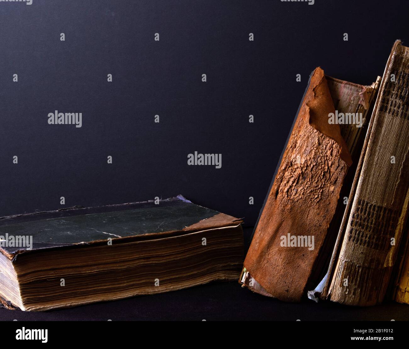 Stack of ancient books with yellowed shabby pages against black fabric Stock Photo