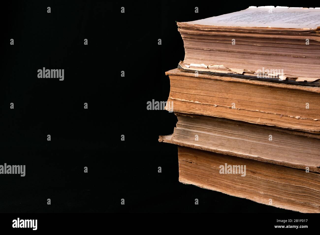 Stack of ancient books with yellowed shabby pages lying on black fabric Stock Photo
