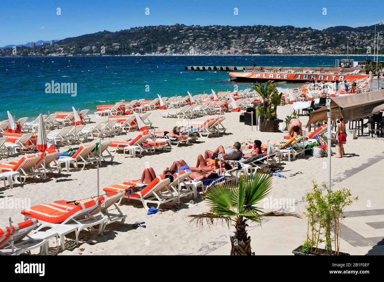 JUAN-LES-PINS, FRANCE - MAY 15: People sunbathing in sunloungers on the beach on May 15, 2015 in Juan-Les-Pins, France. Juan-Les-Pins is a well-known Stock Photo
