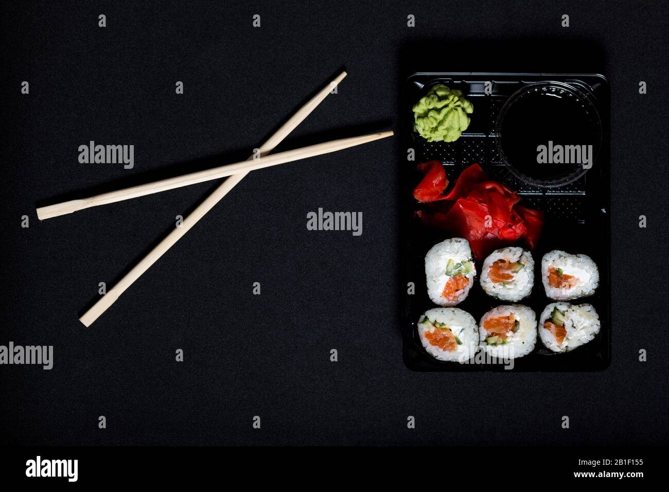 Sushi delivery service. Set of sushi in plastic box on black background. Stock Photo