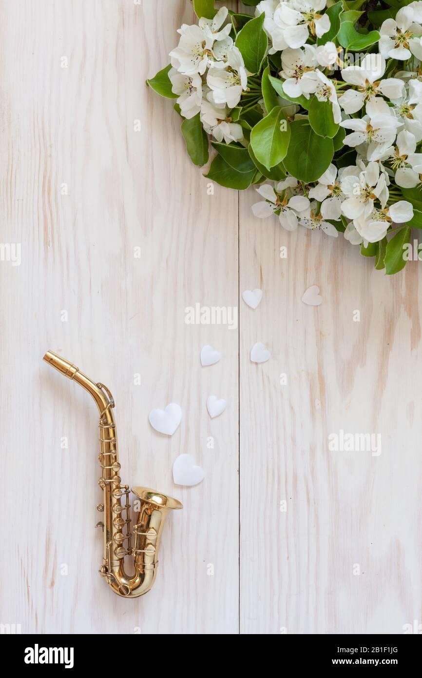 Little Golden saxophone, white heart shape figurines and blossoming apple tree branches. Top