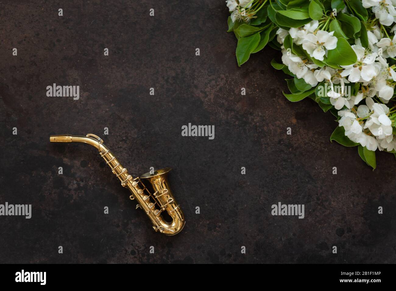 Little Golden saxophone and blossoming apple tree branches. Top view, closeup on white