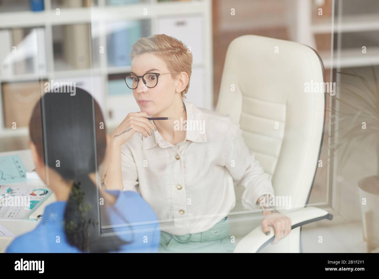Shocked businesswoman talking to colleague in office, copy space Stock Photo