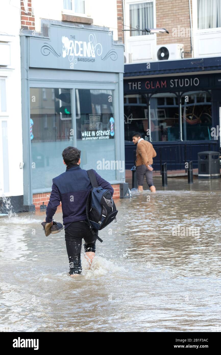 Shrewsbury, Shropshire, UK - Tuesday 25th February 2020 - Locals wade  through the flooding in the Coleham district of the city with their shoes  in their hands. The River Severn will peak