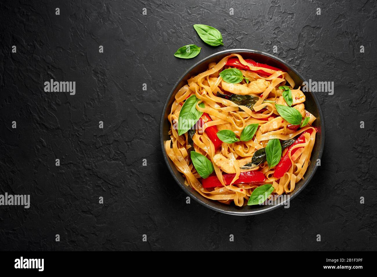 Thai Drunken Noodles or Pad Kee Mao in black bowl at dark slate