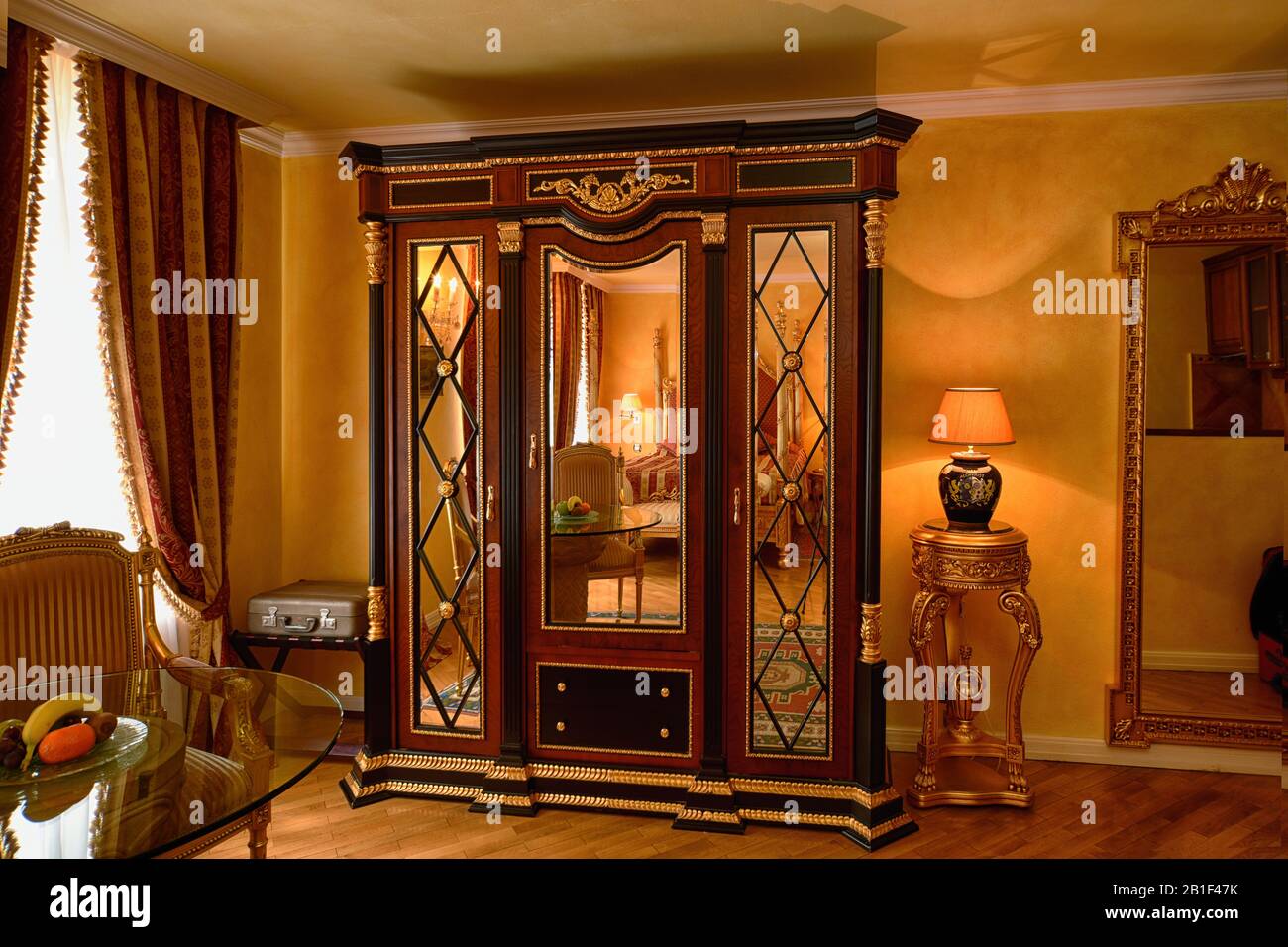 The luxury of a spacious room, Empire style wardrobe, red and gold brocade fabrics decorate a rich; lush, gold gilt furnished hotel room in Prague Stock Photo