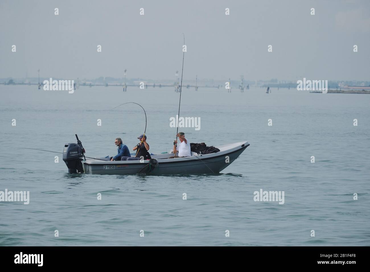 Venice, Italy, friends fishing on the Venetian lagoon, three men in a small open boat with an outboard motor near the island of Burano Stock Photo