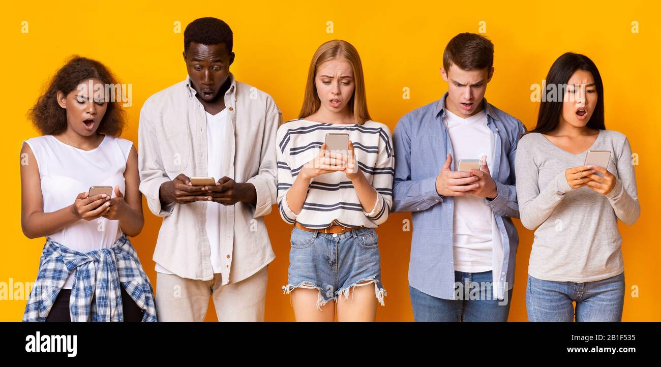 Group of teenagers using mobile phones over yellow background Stock Photo