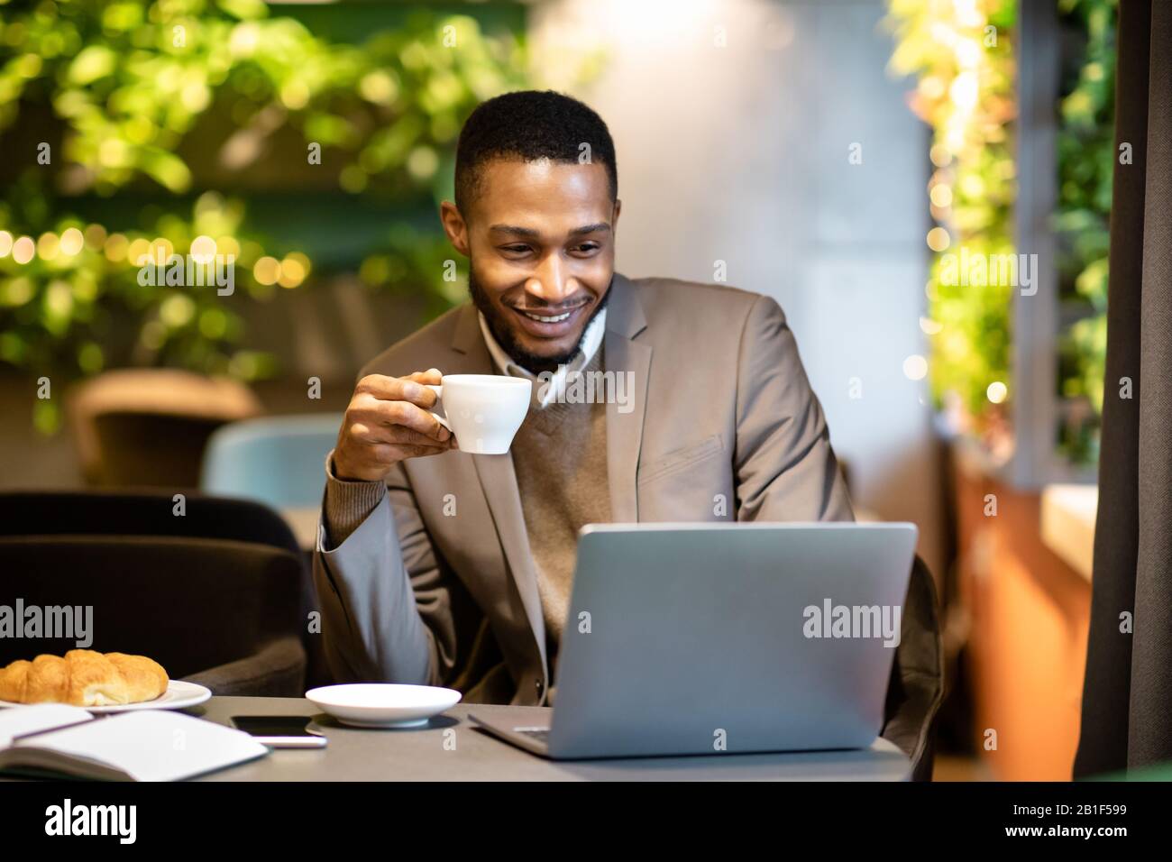 Afro guy drinking tea and using his personal computer Stock Photo - Alamy