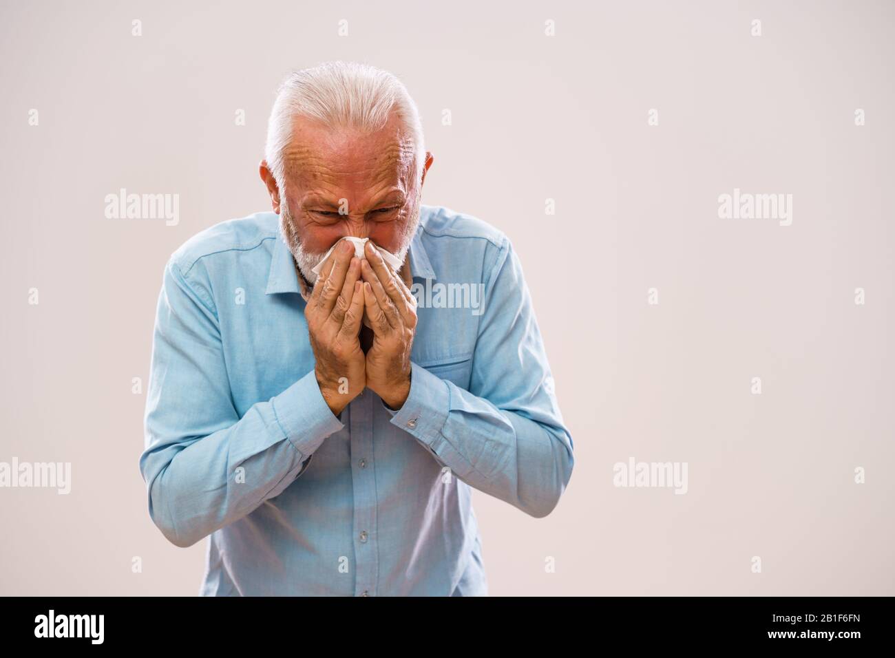 Portrait of senior man who is blowing nose. Stock Photo