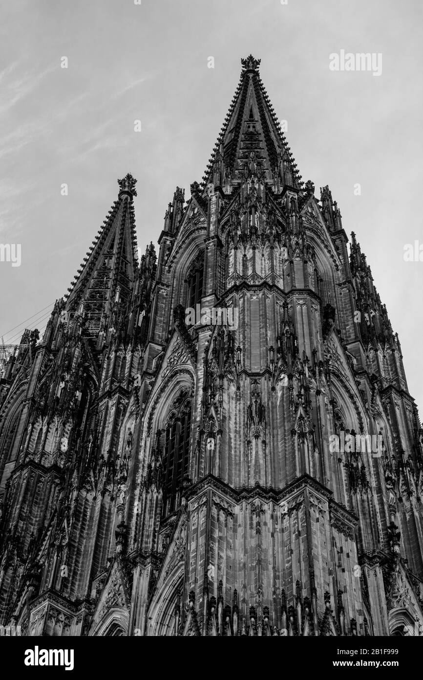 The  facade of the Gothic cathedral of Cologne, with its two spires, reaches to the sky. The black and white photo shows the timelessness. Stock Photo