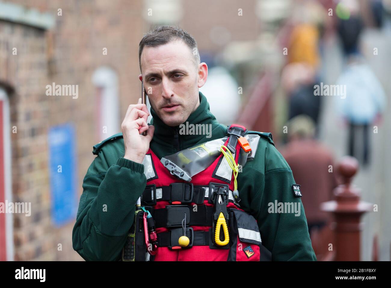 Ironbridge, Shropshire, UK. 25th Feb, 2020. Severe flood warning in place on the River Severn at Ironbridge, Shropshire. A rescue worker keeps up to date on the situation as the river levels continue to rise. Credit: Peter Lopeman/Alamy Live News Stock Photo