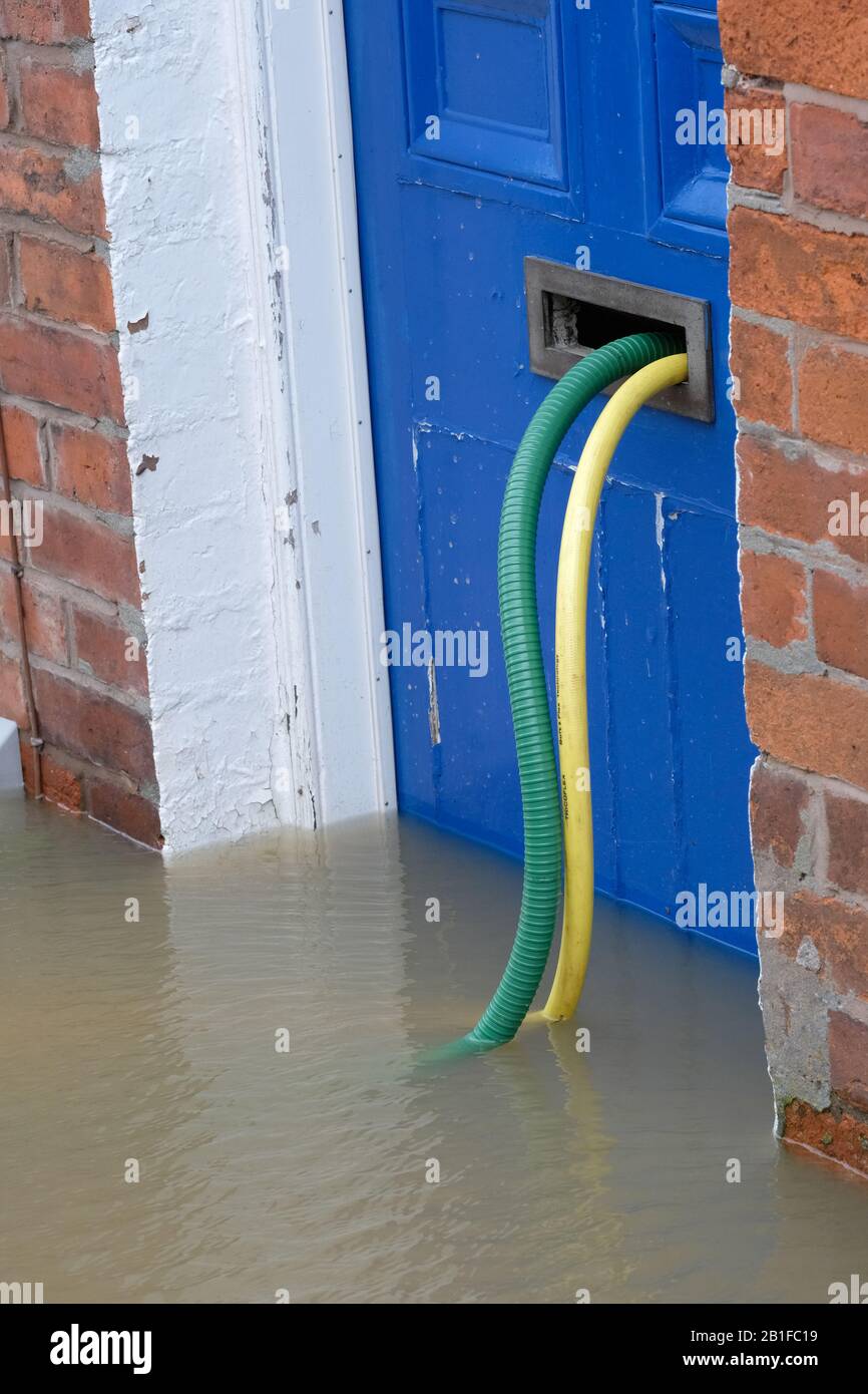 Shrewsbury, Shropshire, UK - Tuesday 25th February 2020 - Desperate householders pump water from their riverside homes via garden hoses through their front door letterboxes. The River Severn will peak later today and a Severe Flood Warning is currently in force for Shrewsbury. Photo Steven May / Alamy Live News Stock Photo