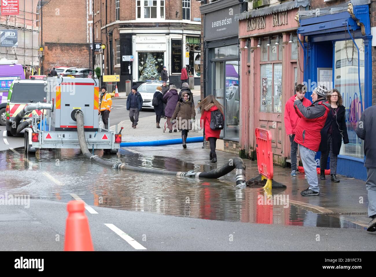 Shrewsbury, Shropshire, UK - Tuesday 25th February 2020 - Flooding in the city centre with an Environment Agency pump trying to control the puddle as shoppers pass by. The River Severn will peak later today and a Severe Flood Warning is currently in force for Shrewsbury. Photo Steven May / Alamy Live News Stock Photo