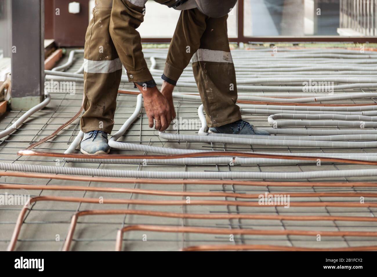 Male plumber worker in uniform holds large round skein of new shiny
