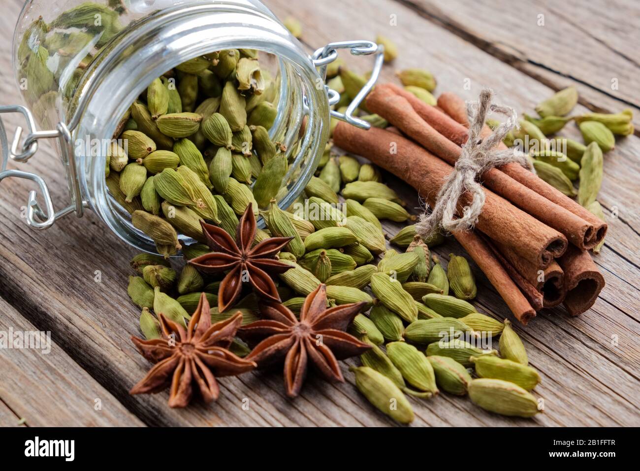 Jar of whole cardamom pods. Cinnamon sticks, cardamom seeds and anise
