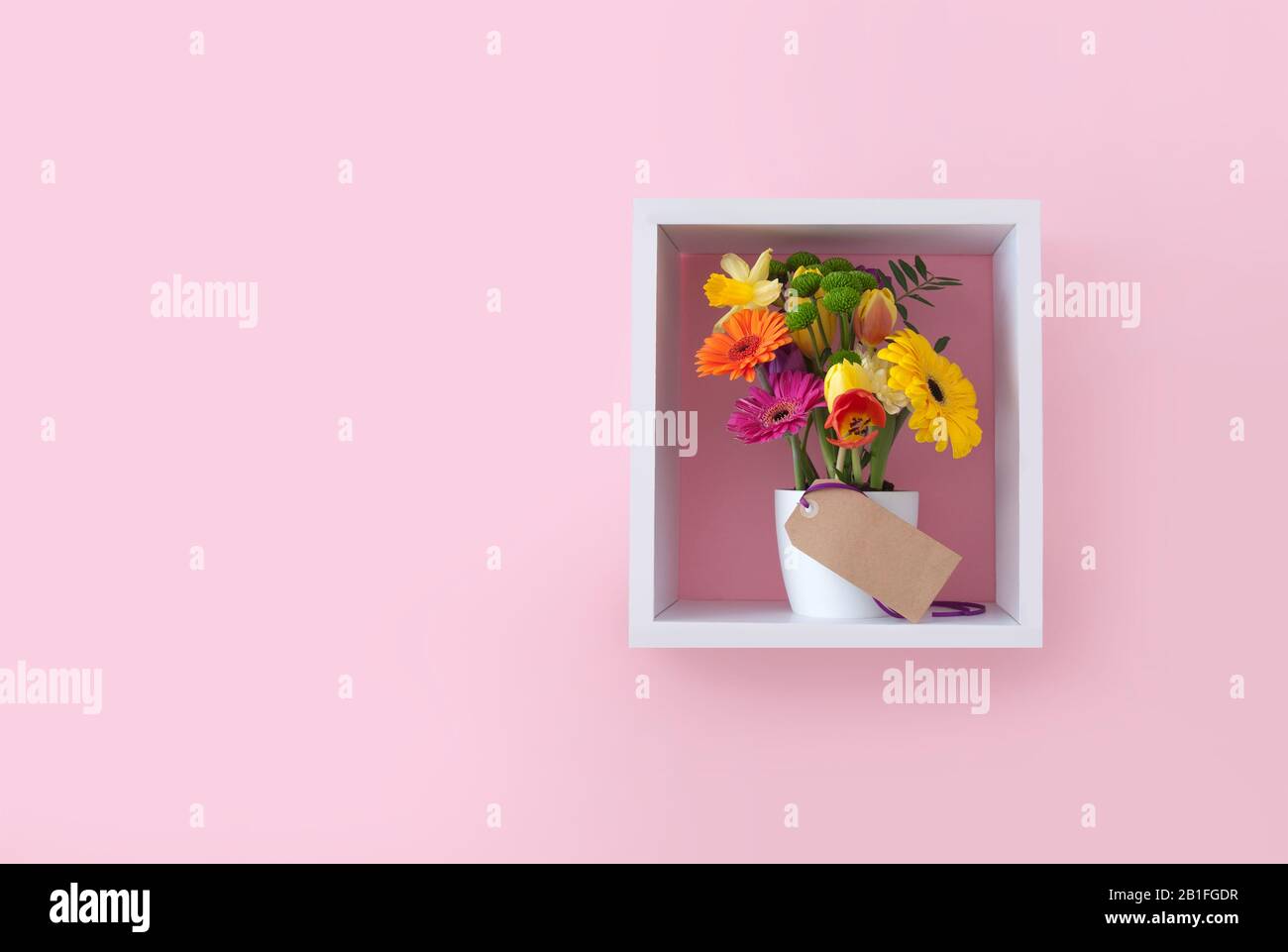 Spring flowers with greeting card in a cube shelf display unit against ...