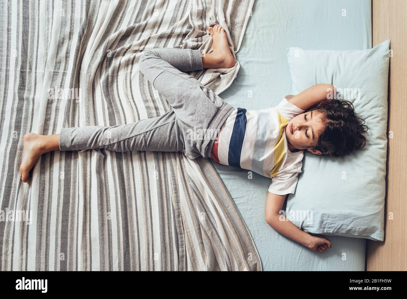 top view of an adorable little girl stretching out in bed in the morning when she just woke up, happy childhood and healthy rest concept Stock Photo