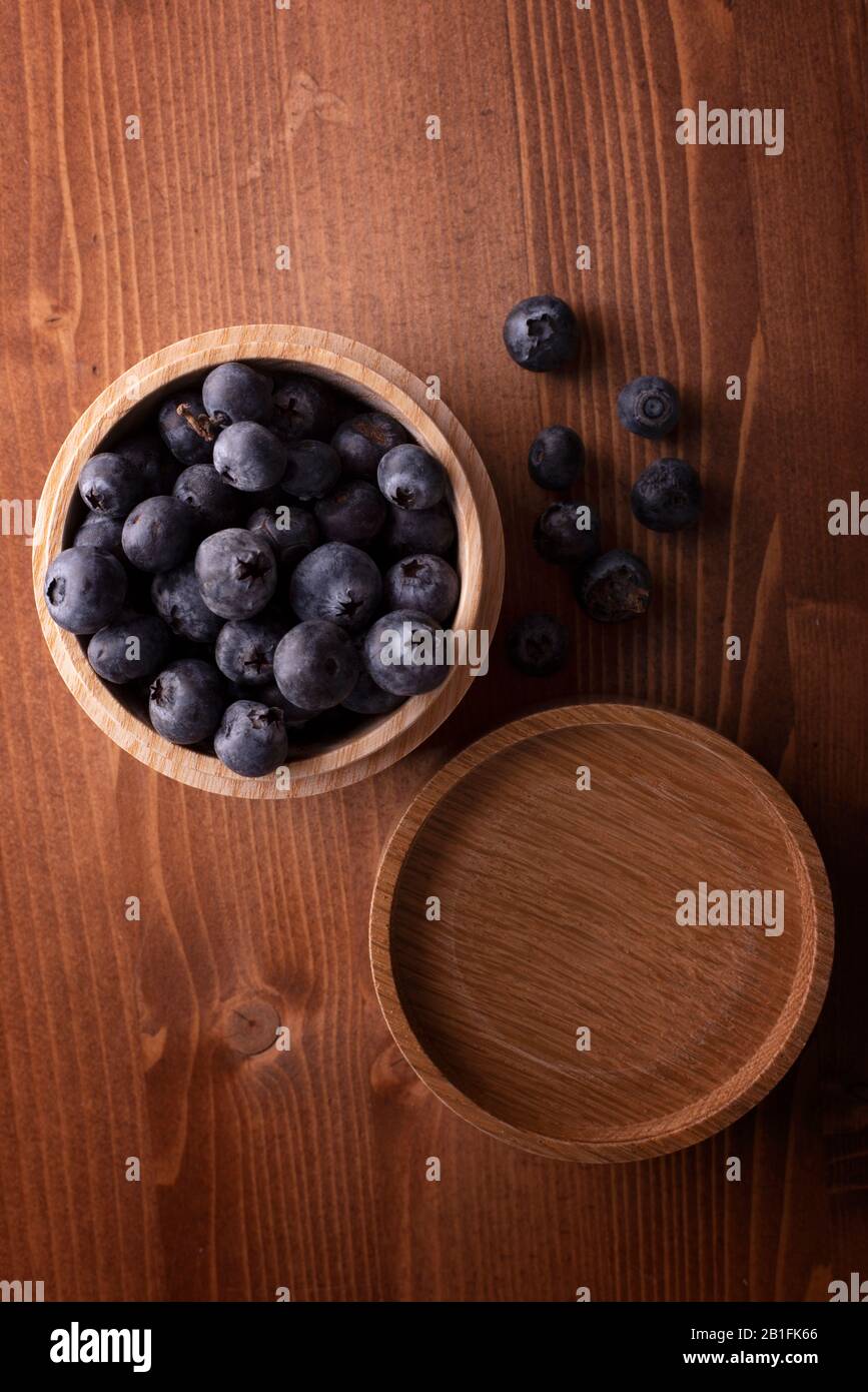 Fresh Blueberries in a wooden bowl on rustic work  surface Stock Photo