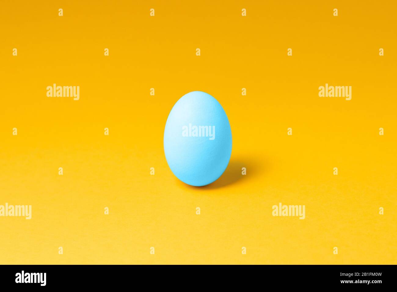 one pastel blue color egg in center on yellow background. easter concept design Stock Photo Alamy