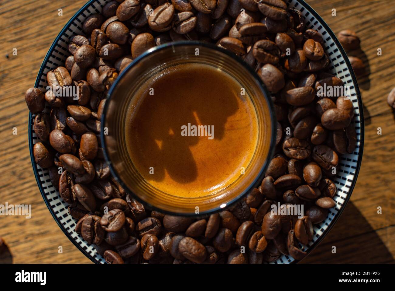 Top down coffe shot of coffe beans in bowl with espresso crema in center . Natural light warm Stock Photo