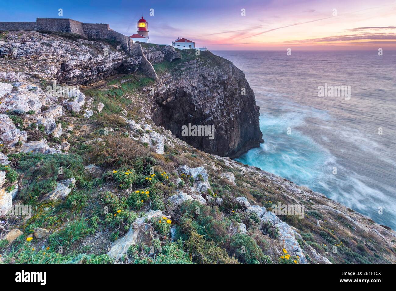 The cliffs and lighthouse of Cabo De San Vicente at sunset, overlooking the Atlantic Ocean. Sagres, Vila do Bispo, Algarve, Portugal, Europe. Stock Photo