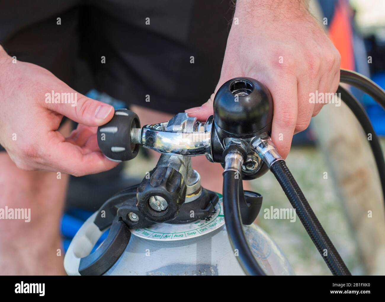Scuba diving equipment close up of a man attaching an Aclamp regulator