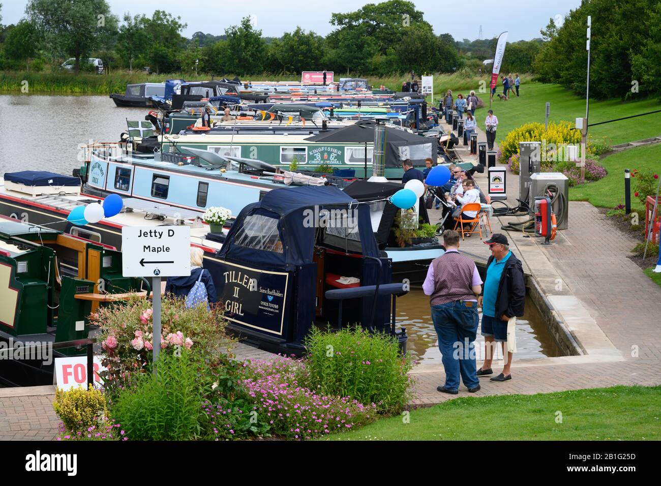 Visitors enjoy a marina's 10th-anniversary celebrations by looking around new and used narrowboats moored beside the pontoons. Stock Photo