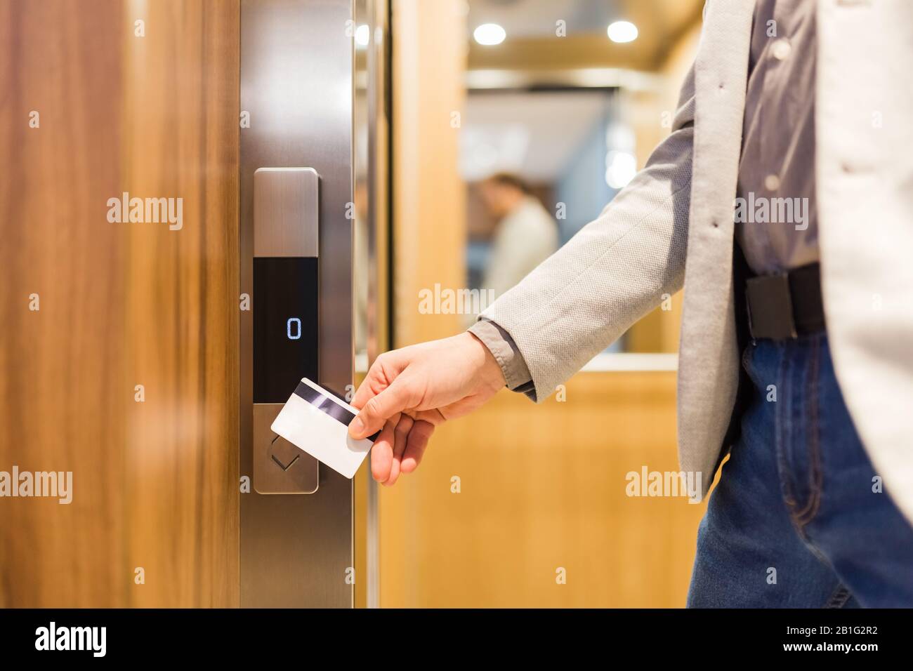 Man holding key card on sensor to open elevator door in modern building
