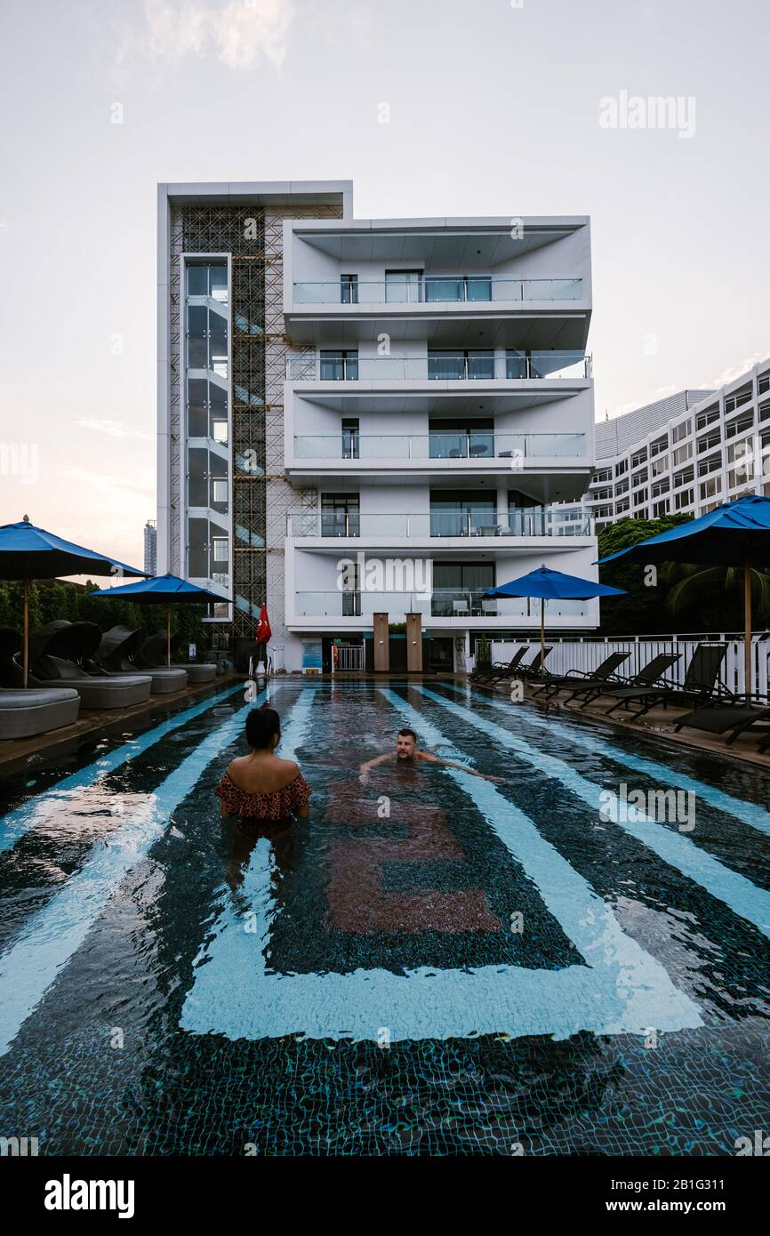 couple in swimming pool during sunrise in Thailand Stock Photo