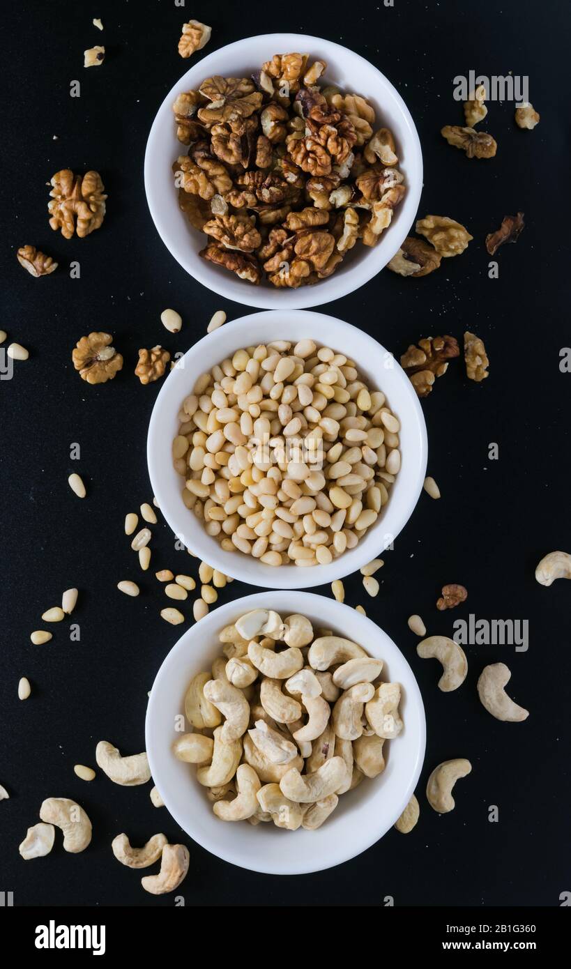 superfood concept, cedar, walnuts, cashew nuts in a plate on a black background Stock Photo