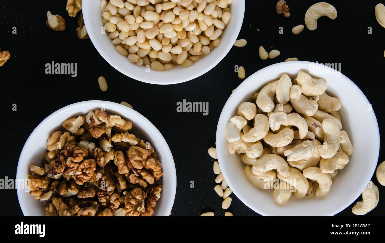superfood concept, cedar, walnuts, cashew nuts in a plate on a black background Stock Photo