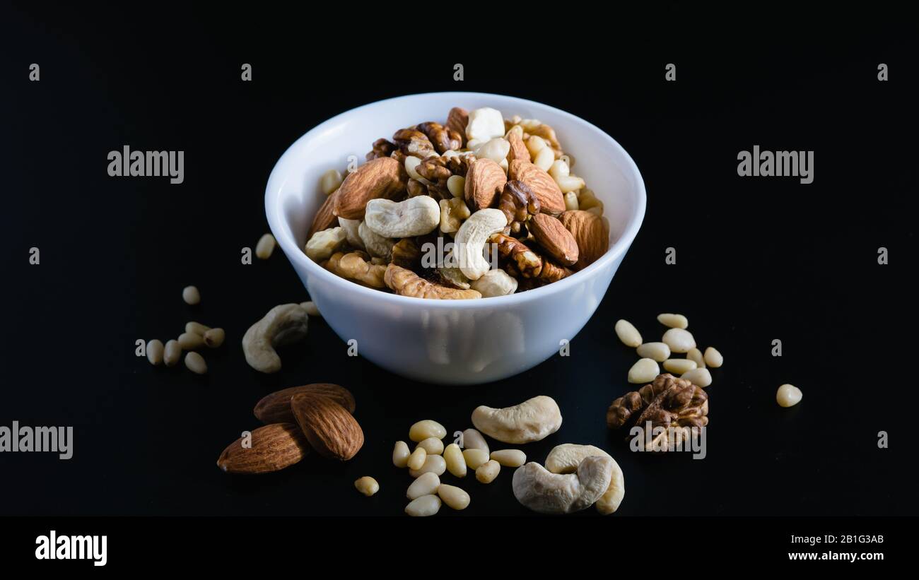 superfood concept, almond, cedar, walnuts, cashew nuts in a plate on a black background Stock Photo