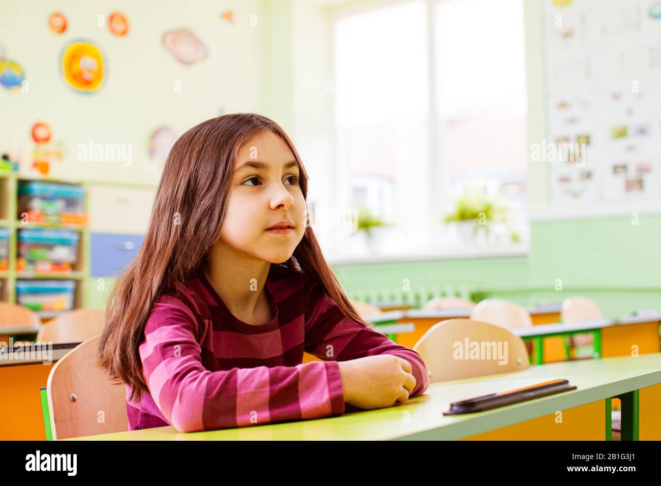 Schoolgirl sitting at her desk in empty classroom Stock Photo - Alamy