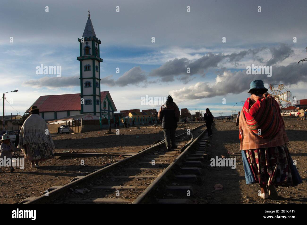 Several indigenous people return to their homes in the city of El Alto after a day's work. They do it following the old railroads of the railroad. Stock Photo