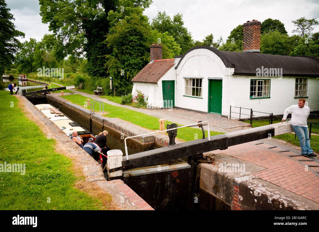 Narrowboat in a lock by a barrel roof cottage on the Stratford Canal, Worcestershire,  England, UK, Britain, Stock Photo