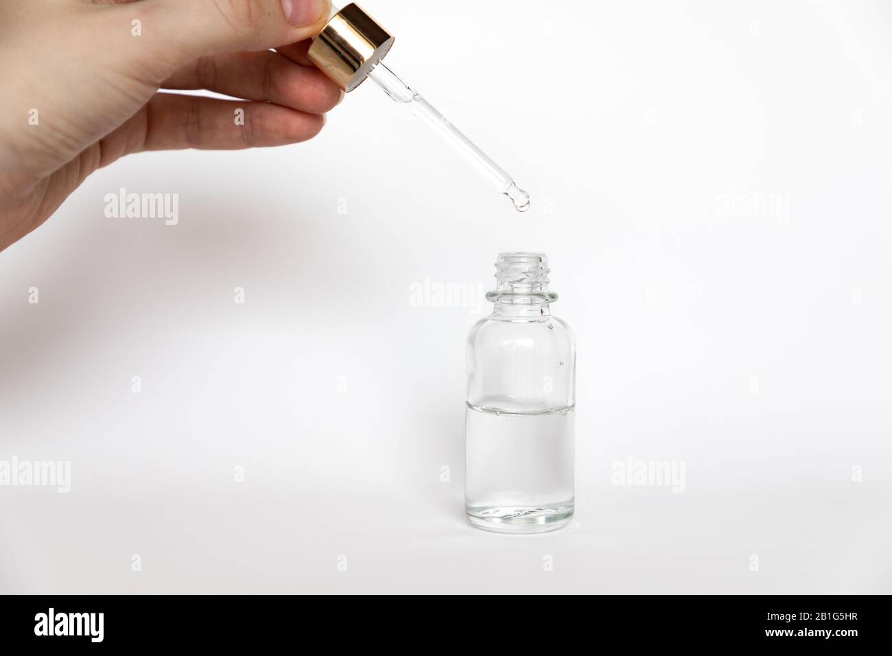 Hyaluronic acid drop falls from cosmetic pipette on white background, Dropper glass Bottle Mock-Up Stock Photo