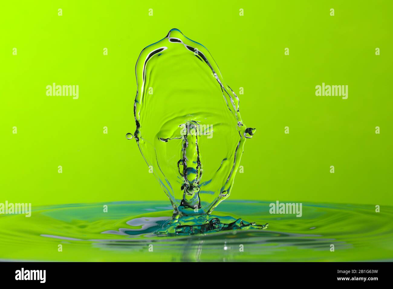 Abstract photograph of a water drop collision created with two water drops  splashing together isolated against a bright green background Stock Photo -  Alamy