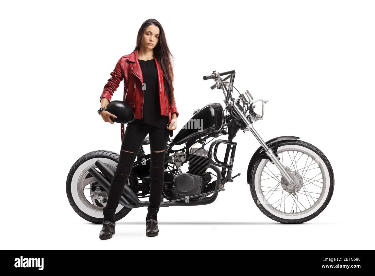 Full length portrait of a young woman holding a helmet and standing next to a custom motorcycle isolated on white background Stock Photo