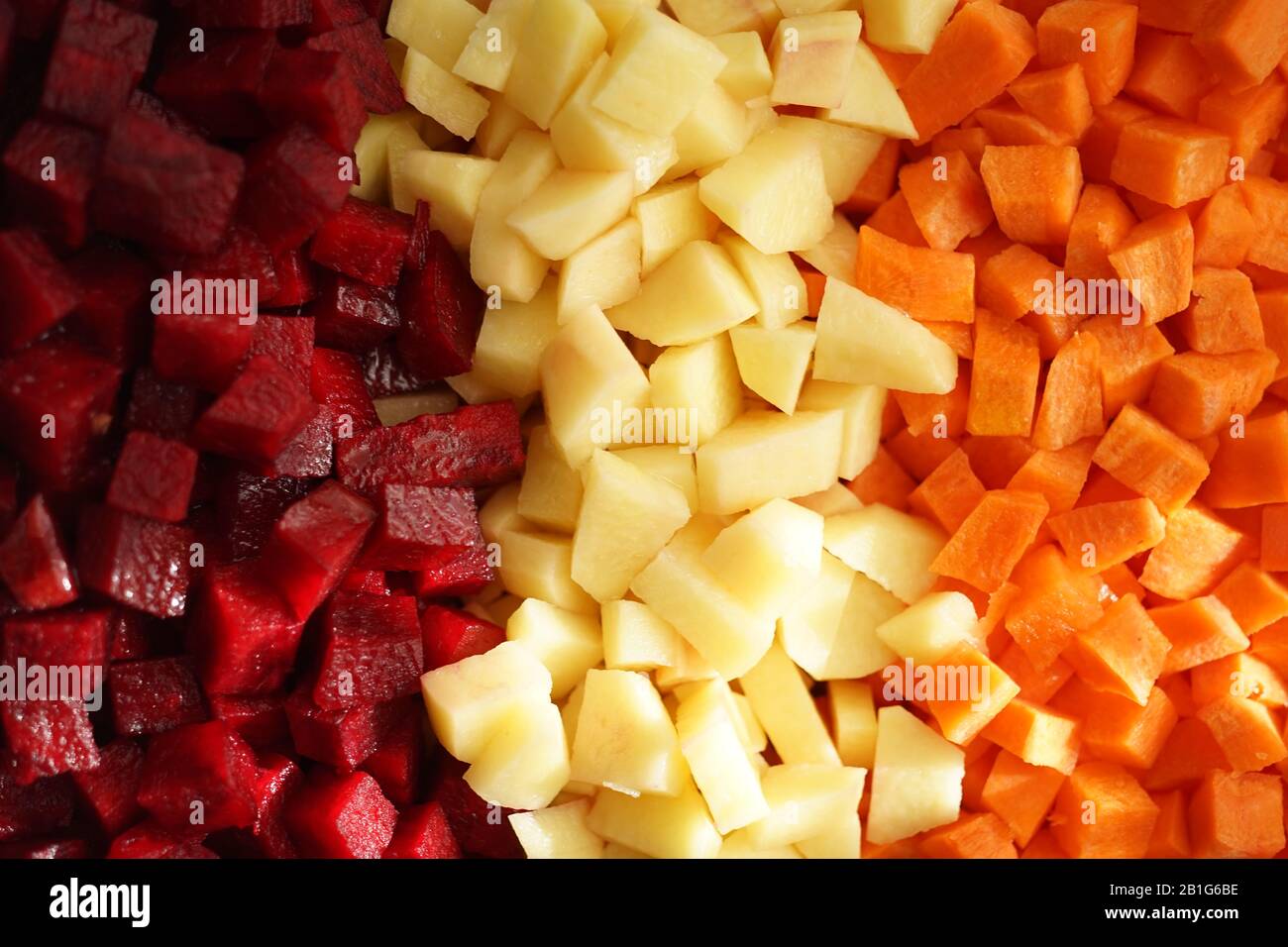 Square raw sliced beets, potatoes and carrots in three rows background. View from above. Healthy vegan food. The vinaigrette Stock Photo