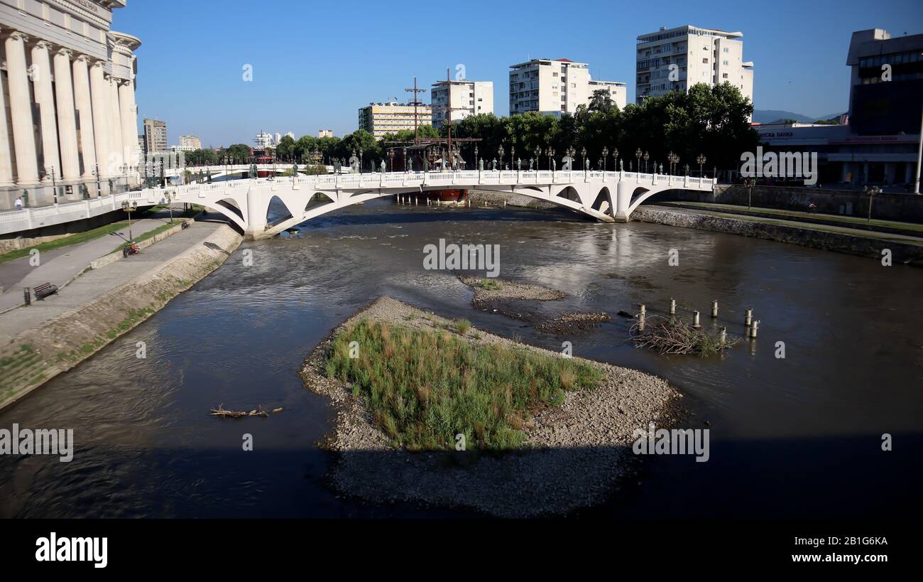 Skopje,North Macedonia,June 27 2019: Low level of water of river Vardar reveal small island with foliage on summer with bridge in central square Stock Photo