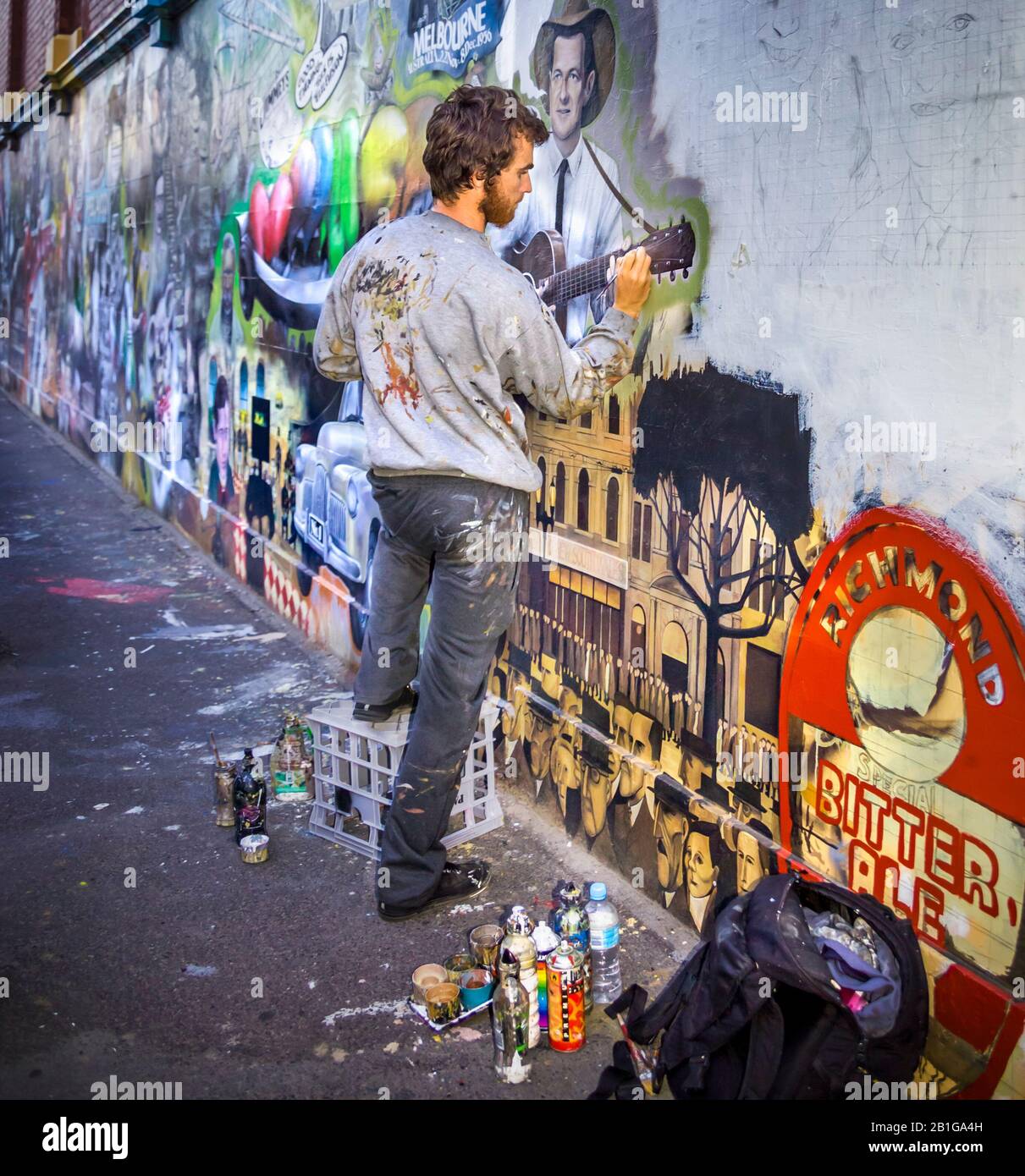Young man,  artist at work painting a mural depicting Melbourne iconic themes, Richmond, Melbourne, Victoria, Australia Stock Photo