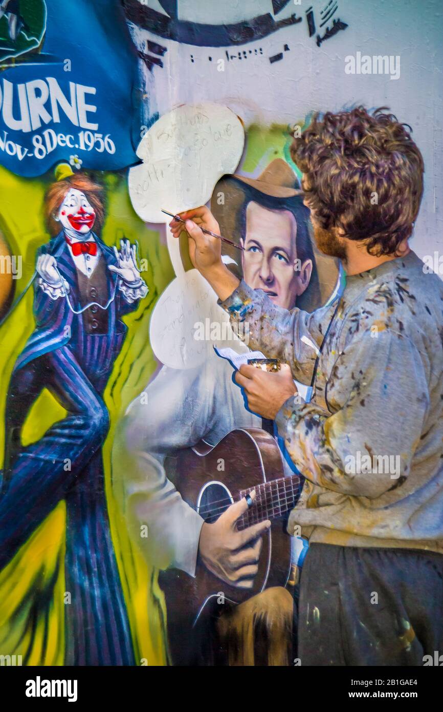 Young man,  artist at work painting a mural depicting Melbourne iconic themes, Richmond, Melbourne, Victoria, Australia Stock Photo