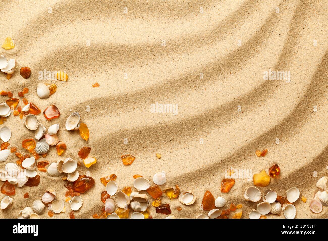 Ambers and seashells on sand background. Flat lay. Top view Stock Photo