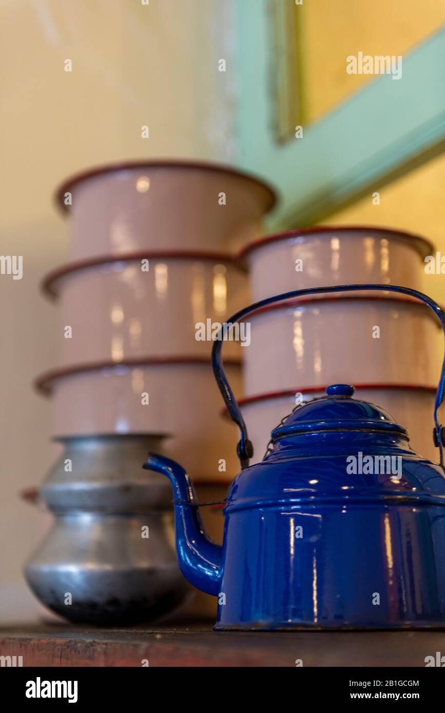 a stack of enameled cookware in a kitchen with a teapot and coloured