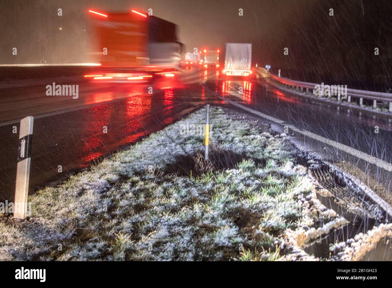 Olpe, Germany. 25th Feb, 2020. Trucks drive on the Autobahn 45 (A45) near Olpe, while the hard shoulder is slightly snowed in. A small low brought winter to North Rhine-Westphalia in the evening hours. Credit: Bernd März/dpa-Zentralbild/dpa/Alamy Live News Stock Photo