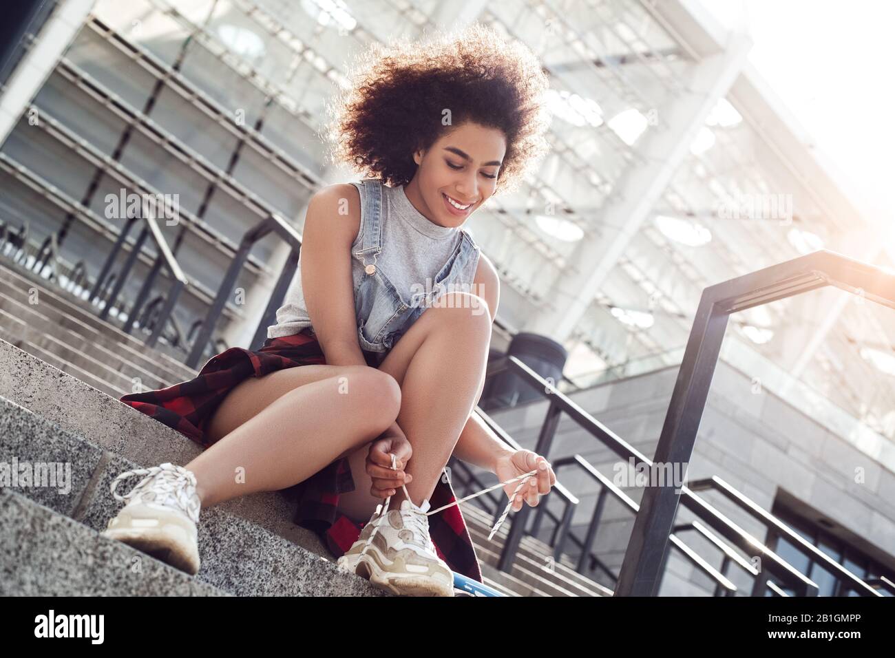 Young woman in the city street sitting on stairs smiling joyful side view Stock Photo