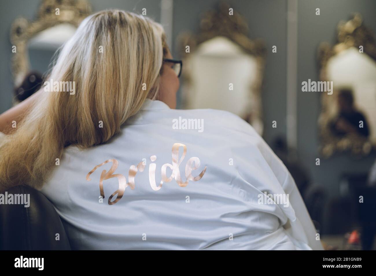 a bride on her wedding day wearing a dressing gown with the word Bride